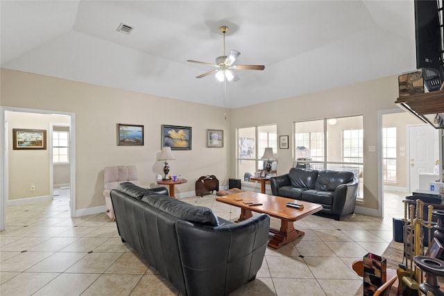 tiled living room with vaulted ceiling, a raised ceiling, and ceiling fan