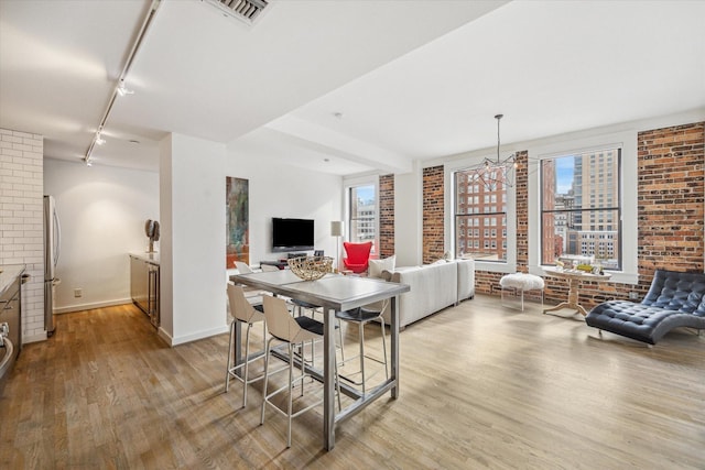 interior space featuring rail lighting, brick wall, and light hardwood / wood-style floors