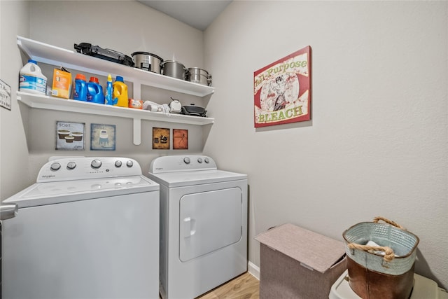 clothes washing area featuring light wood-type flooring, washer and clothes dryer, and laundry area