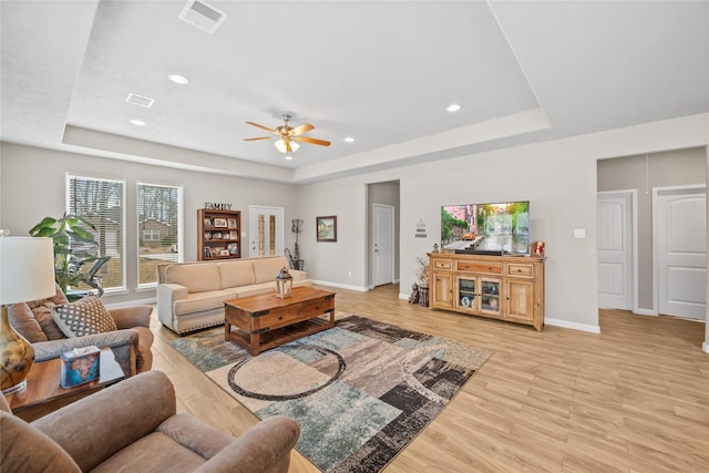 living area featuring baseboards, a tray ceiling, and visible vents