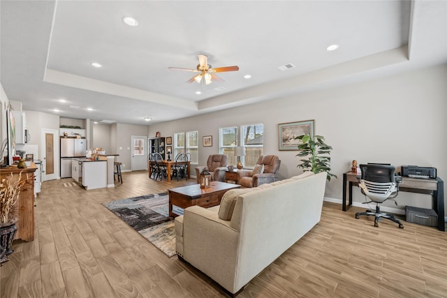 living area featuring a ceiling fan, light wood-style flooring, a raised ceiling, visible vents, and recessed lighting