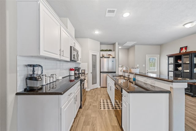 kitchen with stainless steel appliances, visible vents, a sink, and dark countertops