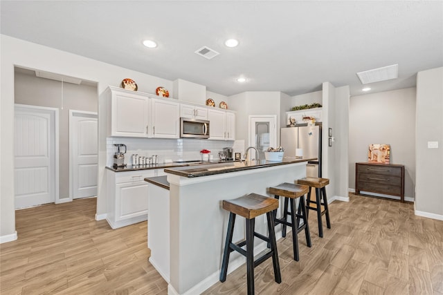 kitchen featuring dark countertops, light wood-type flooring, visible vents, and stainless steel appliances