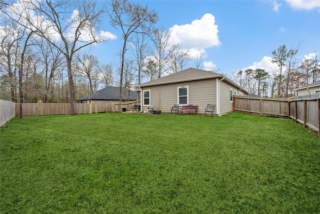 back of property with a lawn, a shingled roof, and a fenced backyard