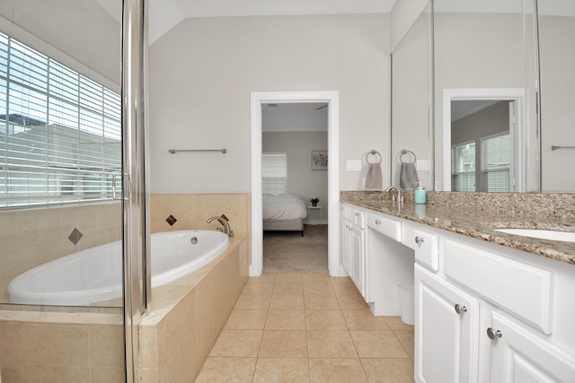 bathroom with vaulted ceiling, vanity, tile patterned flooring, and tiled tub