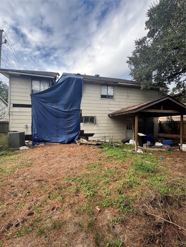 rear view of property featuring a lawn and central air condition unit