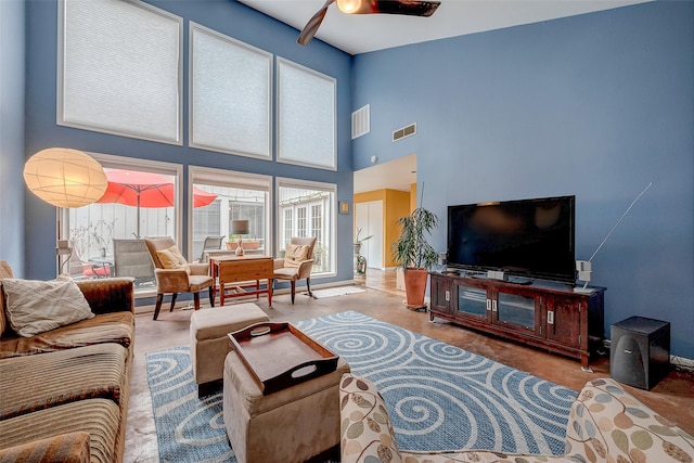 living room featuring a towering ceiling, concrete floors, and ceiling fan