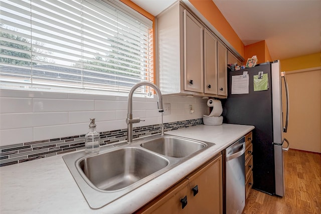 kitchen with tasteful backsplash, stainless steel appliances, sink, and light wood-type flooring