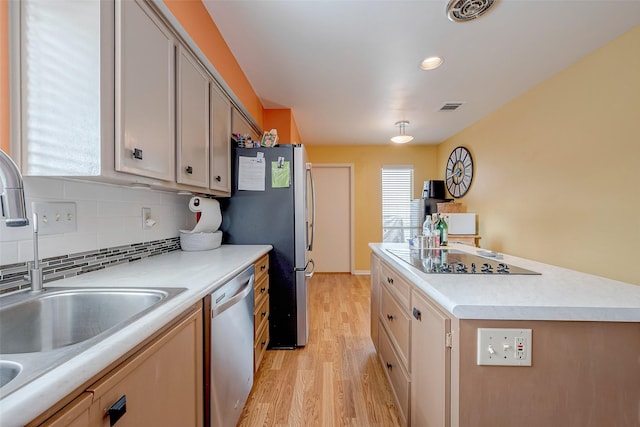 kitchen featuring stainless steel appliances, sink, decorative backsplash, and light hardwood / wood-style flooring