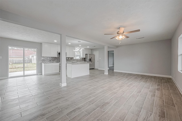 unfurnished living room with a textured ceiling, ceiling fan, and light wood-type flooring