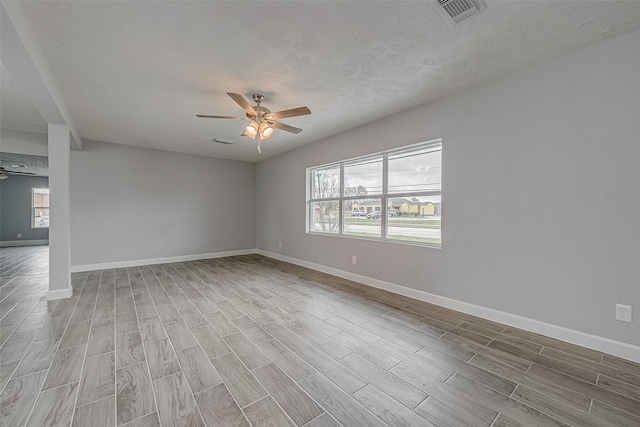 empty room featuring hardwood / wood-style flooring, ceiling fan, a textured ceiling, and a wealth of natural light