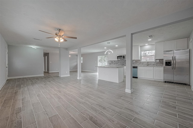 unfurnished living room with sink and ceiling fan