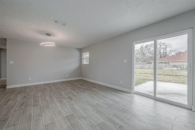 unfurnished room featuring a textured ceiling and light hardwood / wood-style flooring