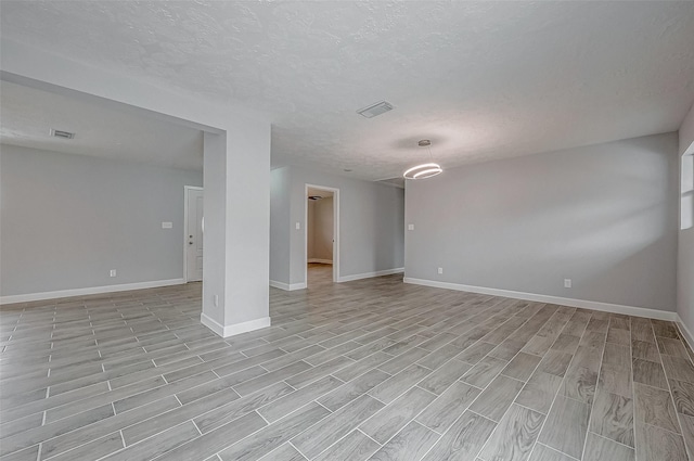 empty room featuring a textured ceiling and light wood-type flooring