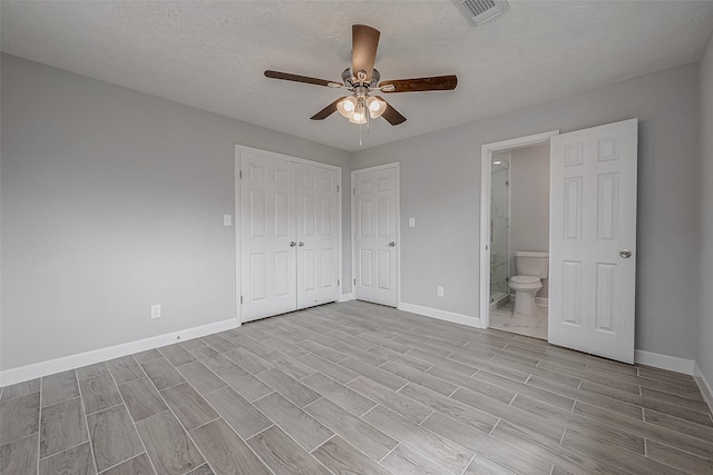 unfurnished bedroom with ensuite bathroom, a textured ceiling, ceiling fan, and a closet