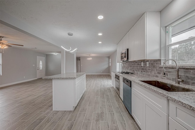 kitchen with pendant lighting, sink, stainless steel appliances, and white cabinets