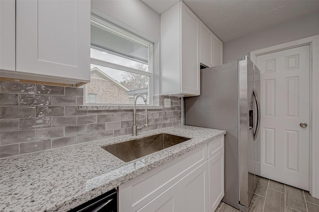 kitchen with sink, light stone countertops, and white cabinets