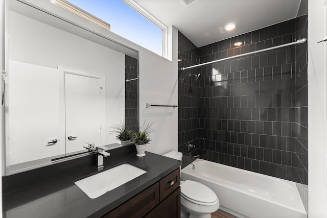 full bathroom featuring vanity, tiled shower / bath combo, and toilet