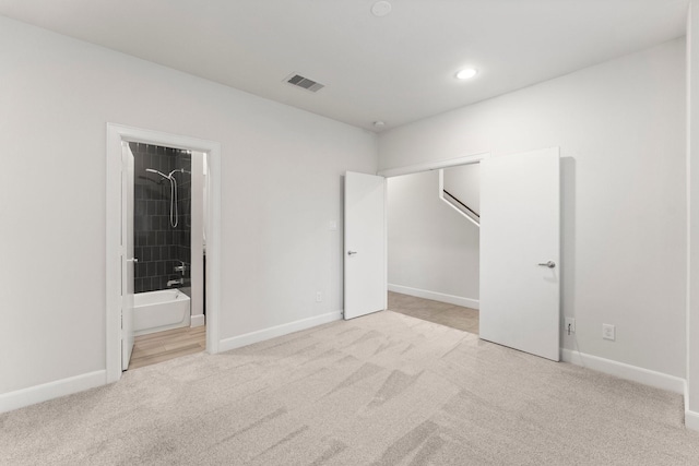 unfurnished bedroom with connected bathroom and light carpet