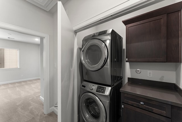 laundry room featuring cabinets, light colored carpet, and stacked washer and clothes dryer