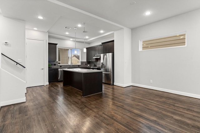 kitchen featuring dark wood-type flooring, sink, decorative light fixtures, a center island, and appliances with stainless steel finishes