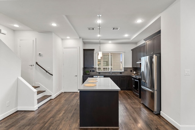 kitchen featuring dark wood-type flooring, hanging light fixtures, backsplash, stainless steel appliances, and a center island