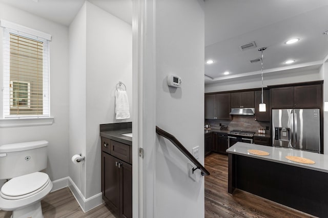 bathroom with tasteful backsplash, vanity, wood-type flooring, and toilet