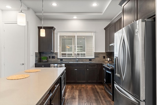 kitchen featuring sink, appliances with stainless steel finishes, dark hardwood / wood-style floors, pendant lighting, and decorative backsplash