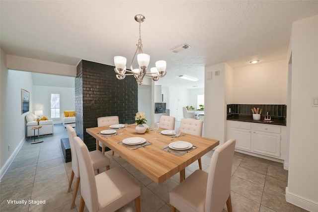 tiled dining area featuring a textured ceiling and a chandelier