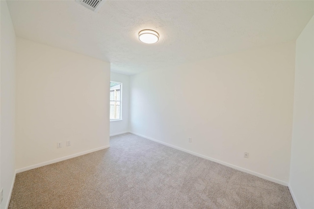 unfurnished room featuring light colored carpet and a textured ceiling