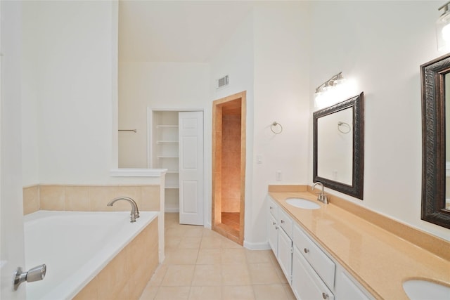 bathroom with vanity, tiled tub, and tile patterned flooring