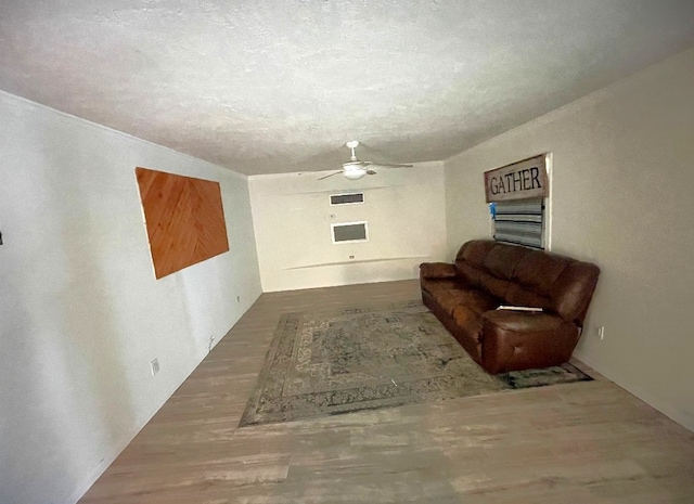 sitting room with hardwood / wood-style floors, ceiling fan, and a textured ceiling