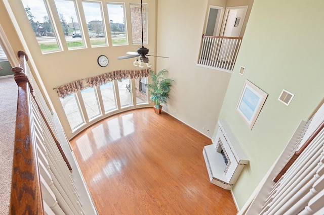 staircase with a towering ceiling, hardwood / wood-style floors, and ceiling fan