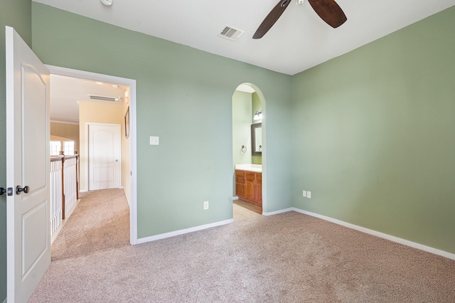 unfurnished bedroom with connected bathroom, light carpet, and ceiling fan