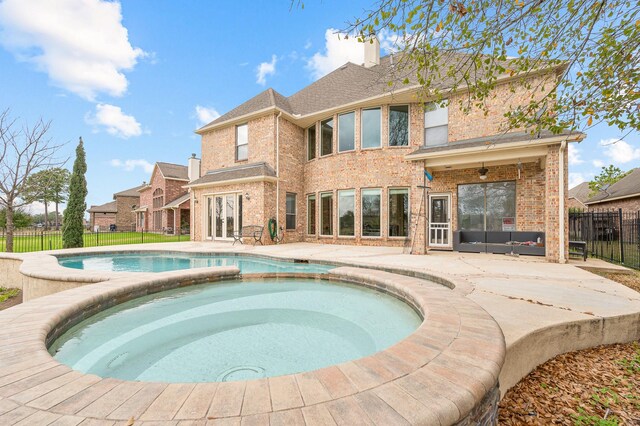 rear view of property featuring a patio, french doors, and an in ground hot tub