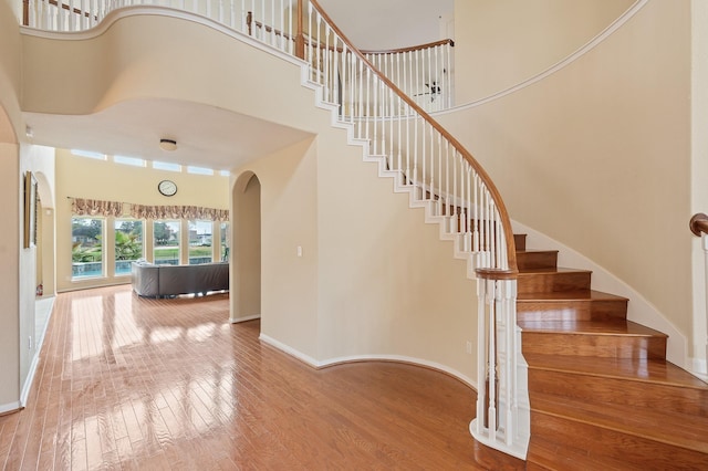 staircase with hardwood / wood-style floors and a high ceiling