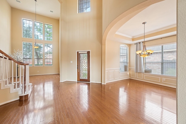 entrance foyer with an inviting chandelier, hardwood / wood-style flooring, plenty of natural light, and crown molding