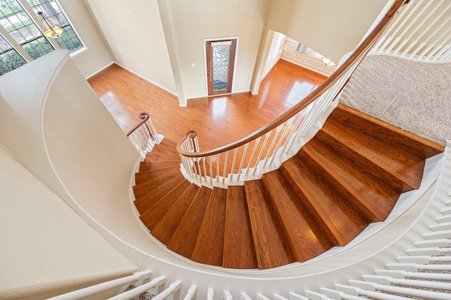 stairway with hardwood / wood-style floors, a towering ceiling, and plenty of natural light