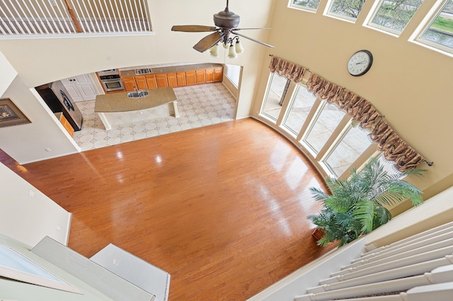 living room featuring hardwood / wood-style floors, ceiling fan, a healthy amount of sunlight, and a high ceiling