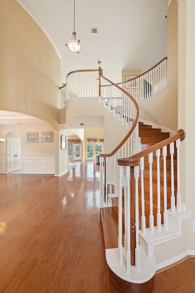 stairway featuring crown molding, hardwood / wood-style flooring, and a high ceiling