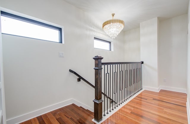 stairway featuring hardwood / wood-style flooring and a notable chandelier