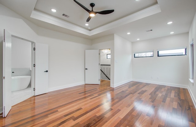 unfurnished bedroom featuring crown molding, wood-type flooring, and a tray ceiling