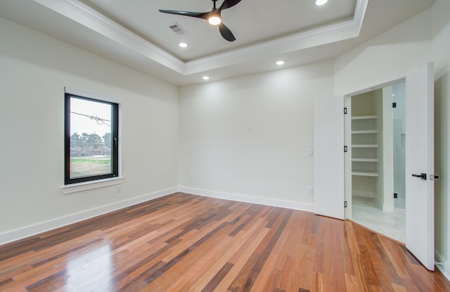 spare room featuring hardwood / wood-style flooring, ornamental molding, a raised ceiling, and ceiling fan