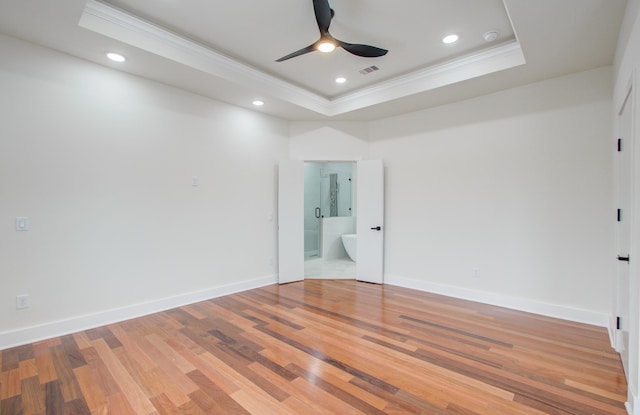 spare room featuring ornamental molding, wood-type flooring, ceiling fan, and a tray ceiling