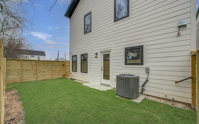 rear view of house with central AC and a yard