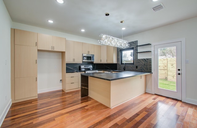 kitchen featuring decorative light fixtures, kitchen peninsula, decorative backsplash, and appliances with stainless steel finishes