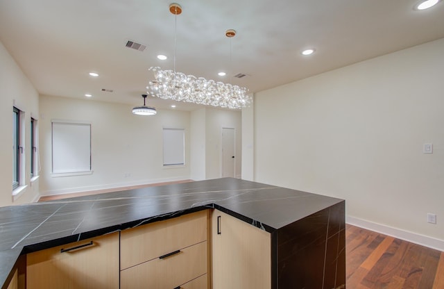 kitchen with hanging light fixtures, dark hardwood / wood-style floors, and light brown cabinets