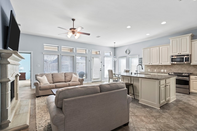 living room with ceiling fan, a high end fireplace, and sink