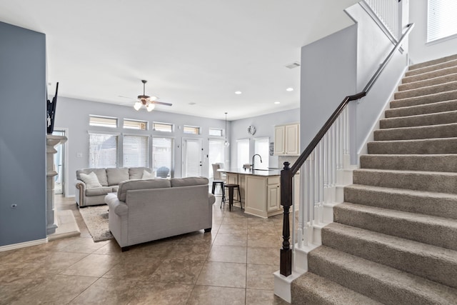 living room with ceiling fan, plenty of natural light, sink, and light tile patterned floors