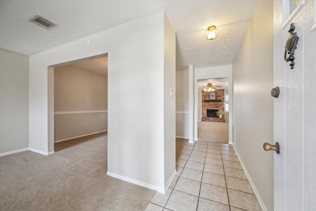 hall featuring light colored carpet and a textured ceiling